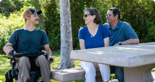 Three people sitting at a park table